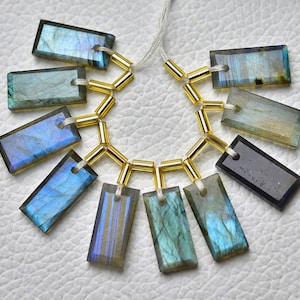 May include: A strand of gold beads with 10 iridescent labradorite gemstone rectangular pendants. The pendants are various shades of blue, green, and gray.