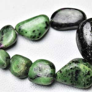 May include: A strand of green and black gemstone beads. The beads are smooth and polished, and they have a natural, organic look. The beads are strung on a wire, and they are ready to be used in jewelry making.