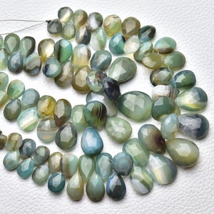 Könnte beinhalten: Eine Strähne aus grünen, blauen und braunen Achat-Edelsteinkugeln. Die Kugeln sind facettiert und haben eine Tropfenform.