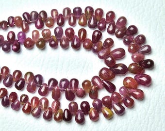 May include: A collection of polished, teardrop-shaped gemstones in deep red, purple, and yellow hues. The beads are strung, displaying their natural colour variations and translucence. Suitable for jewellery making, each bead is unique.