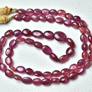 Peut inclure: Un collier de perles de rubis roses ovales avec un pendentif en or.