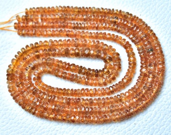 May include: A strand of orange gemstone beads, likely citrine, with a faceted, slightly irregular shape. The beads are strung on a thin cord and are arranged in a circular pattern.