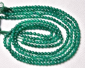 May include: A strand of green gemstone beads. The beads are faceted and have a round shape. The beads are strung on a thin cord and are ready to be used for jewelry making.