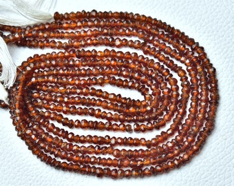May include: A strand of brown gemstone beads. The beads are faceted and have a slightly irregular shape. The beads are strung on a white thread.