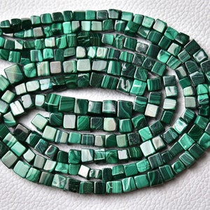 Puede incluir: Una hebra de cuentas de malaquita verde, cada cuenta es de forma cuadrada con un acabado liso y pulido.