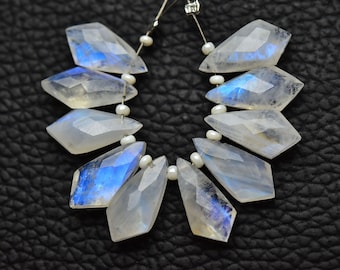 Peut inclure: Un brin de perles de pierre de lune blanche irisée de forme facetée en goutte. Les perles sont enfilées sur un fil d'argent avec de petits espaceurs de perles blanches.
