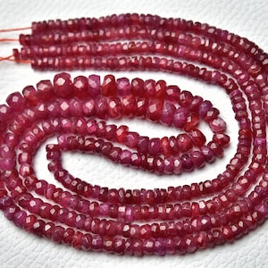 Puede incluir: Una hebra de cuentas de piedras preciosas de color rojo rubí, facetadas y pulidas, enhebradas en un hilo fino. Las cuentas están dispuestas en un patrón circular, creando un collar o una pulsera.