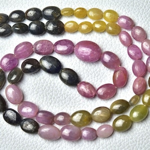 May include: A strand of oval-shaped gemstone beads in shades of blue, pink, and green. The beads are arranged in a gradient pattern, with the blue beads at one end, the pink beads in the middle, and the green beads at the other end.