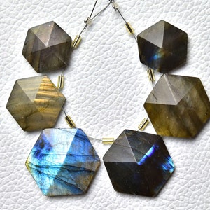 May include: A strand of six faceted labradorite gemstone beads, each with a star-shaped design. The beads are strung on a silver wire with gold-colored spacers.