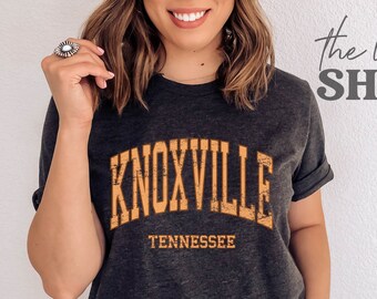 May include: Dark grey heather t-shirt with a distressed orange graphic that says "Knoxville, Tennessee".