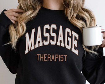 May include: Black sweatshirt with the text "MASSAGE THERAPIST" in white and brown lettering.