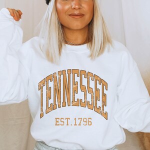 Puede incluir: Sudadera blanca con un gr&aacute;fico vintage marr&oacute;n que dice "Tennessee Est. 1796".