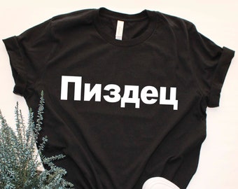 May include: Black t-shirt with the Russian word "Пиздец" printed in white on the front.