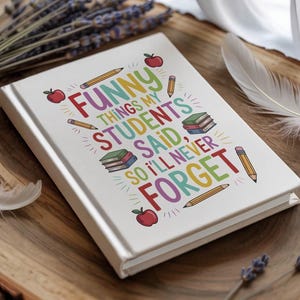 May include: A white notebook with the text "Funny Things My Students Said, So I'll Never Forget" in colorful letters. The cover design includes illustrations of pencils, apples, and books. The notebook is a teacher's journal.
