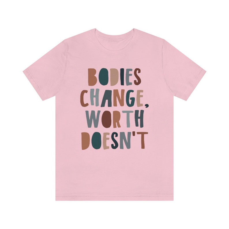 May include: Pink t-shirt with the text "BODIES CHANGE, WORTH DOESN'T" in colorful, stylized lettering.