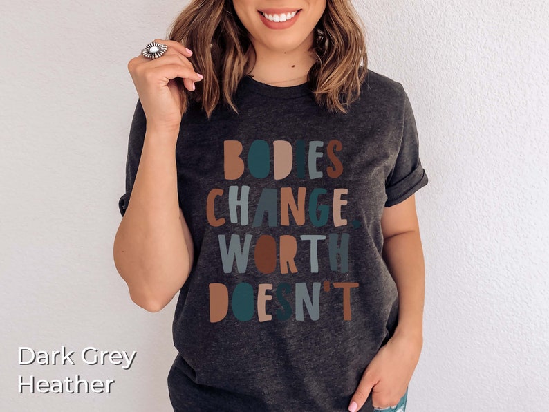 May include: Dark grey heather t-shirt with the text "BODIES CHANGE, WORTH DOESN'T" in colorful block letters.