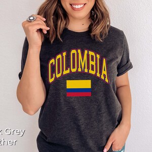 K&ouml;nnte beinhalten: Dunkelgraues T-Shirt mit dem Wort "KOLUMBIEN" in Gelb mit rotem Rand und einer darunter liegenden gelben, blauen und roten Flagge.