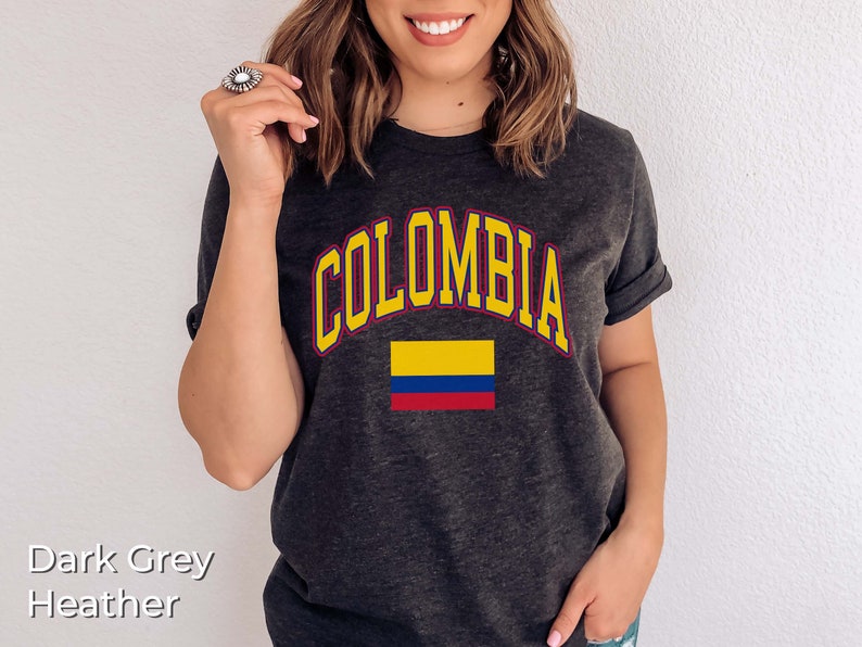 K&ouml;nnte beinhalten: Dunkelgraues T-Shirt mit dem Wort "KOLUMBIEN" in Gelb mit rotem Rand und einer darunter liegenden gelben, blauen und roten Flagge.