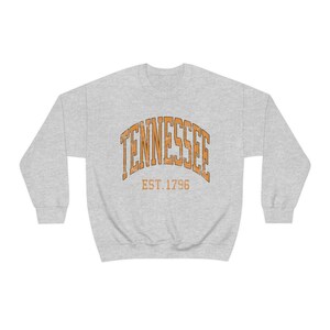 Puede incluir: Una sudadera gris con el texto "TENNESSEE EST. 1796" en naranja.