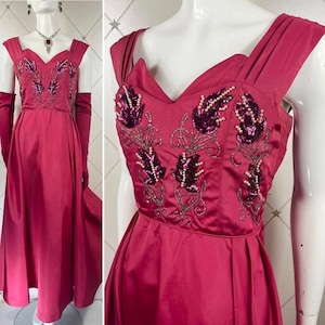 May include: A vintage, floor-length, crimson satin gown with a sweetheart neckline and beaded floral embroidery. The gown has a fitted bodice and a full skirt.
