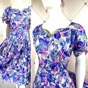 May include: A vintage dress with a sweetheart neckline and short sleeves. The dress is made of a light blue fabric with a pink and white floral print. The dress has a fitted bodice and a full skirt.