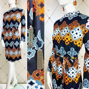May include: A blue, orange and white patterned dress with long sleeves and a high neckline. The dress has a geometric design and a tassel detail at the waist.
