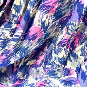 May include: Abstract fabric with a white background and a blue, purple, and pink brushstroke pattern.