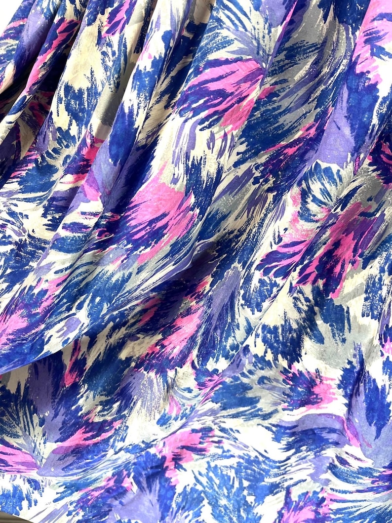 May include: Abstract fabric with a white background and a blue, purple, and pink brushstroke pattern.