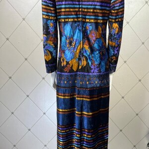 May include: A long blue velvet dress with a floral print and striped pattern. The dress has a high neck and long sleeves.