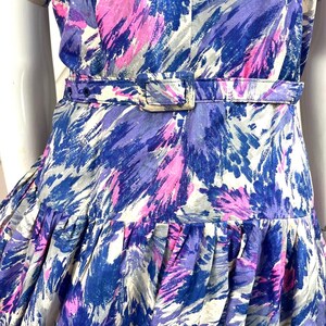 May include: A blue, pink, and white patterned dress with a fitted bodice and a full skirt. The dress has a belt at the waist.