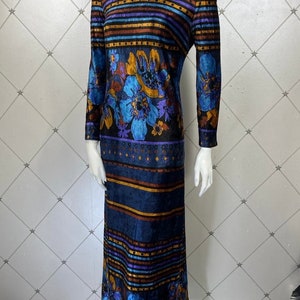 May include: A long-sleeved maxi dress with a high neck and a colorful floral and striped pattern. The dress is made of a soft, velvety fabric and has a fitted silhouette.