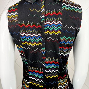 May include: Black sleeveless dress with a colorful wavy pattern and a white collar. The dress has a zipper down the back.