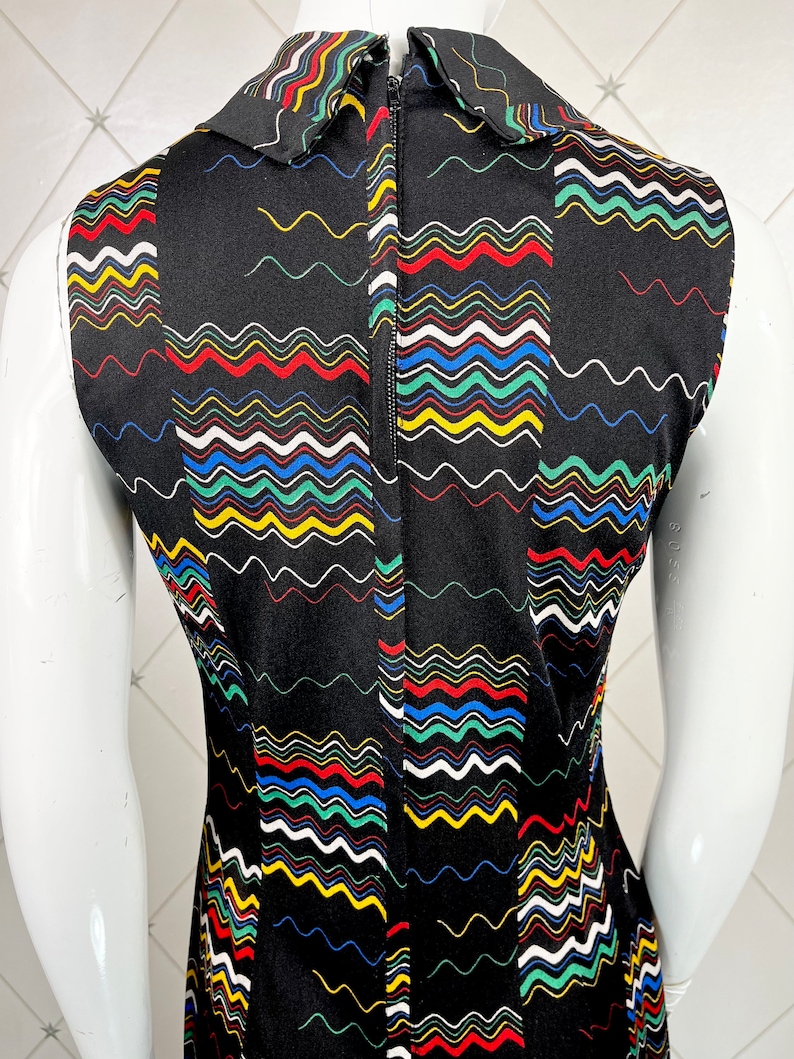 May include: Black sleeveless dress with a colorful wavy pattern and a white collar. The dress has a zipper down the back.