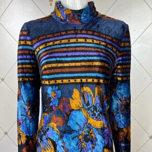 May include: A long-sleeved, high-necked dress with a blue, purple, orange, and brown floral pattern on a black background. The dress has a striped pattern around the neck and waist.