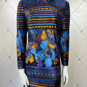 May include: A long-sleeved, blue velvet dress with a high neck and a colorful floral pattern. The dress has a striped pattern with brown, blue, and purple stripes.
