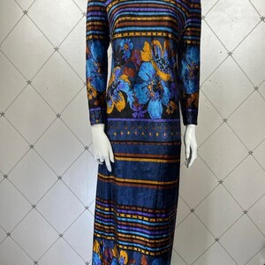 May include: A long-sleeved maxi dress with a high neck and a colorful floral and striped pattern. The dress is made of a soft, velvety fabric and has a relaxed fit.