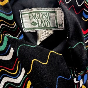 May include: Black fabric with a colorful wavy pattern and a white tag that says "English Lady" with a green leaf logo and the number "14" on it.