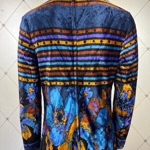 May include: A long-sleeved dress with a high neck and a zipper down the back. The dress is made of a dark blue velvet fabric with a colorful floral and striped pattern.