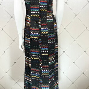 May include: A sleeveless maxi dress with a black background and a colorful wavy pattern. The dress has a collared neckline and a zipper closure in the back.