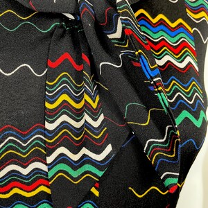 May include: A black sleeveless top with a colorful wavy pattern and a bow tie at the neck.