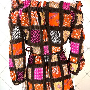 K&ouml;nnte beinhalten: Ein braunes, pinkfarbenes und orangefarbenes Patchworkkleid mit langen &Auml;rmeln und einem quadratischen Ausschnitt. Das Kleid hat einen Rei&szlig;verschluss auf der R&uuml;ckseite und einen G&uuml;rtel.