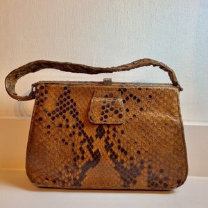 May include: A vintage brown snakeskin handbag with a clasp closure and a short strap.