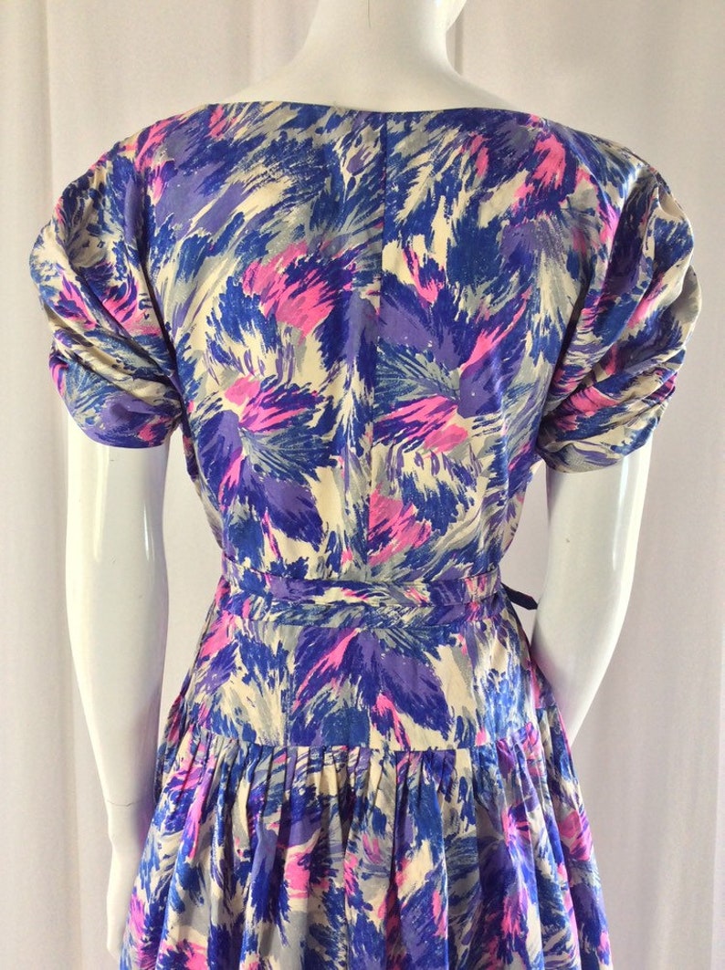 May include: A vintage dress with a floral print in shades of blue, pink, and white. The dress has a fitted bodice and a full skirt. The sleeves are short and puffed.