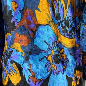 May include: A blue, black, and gold fabric with a floral pattern. The fabric has a velvety texture.