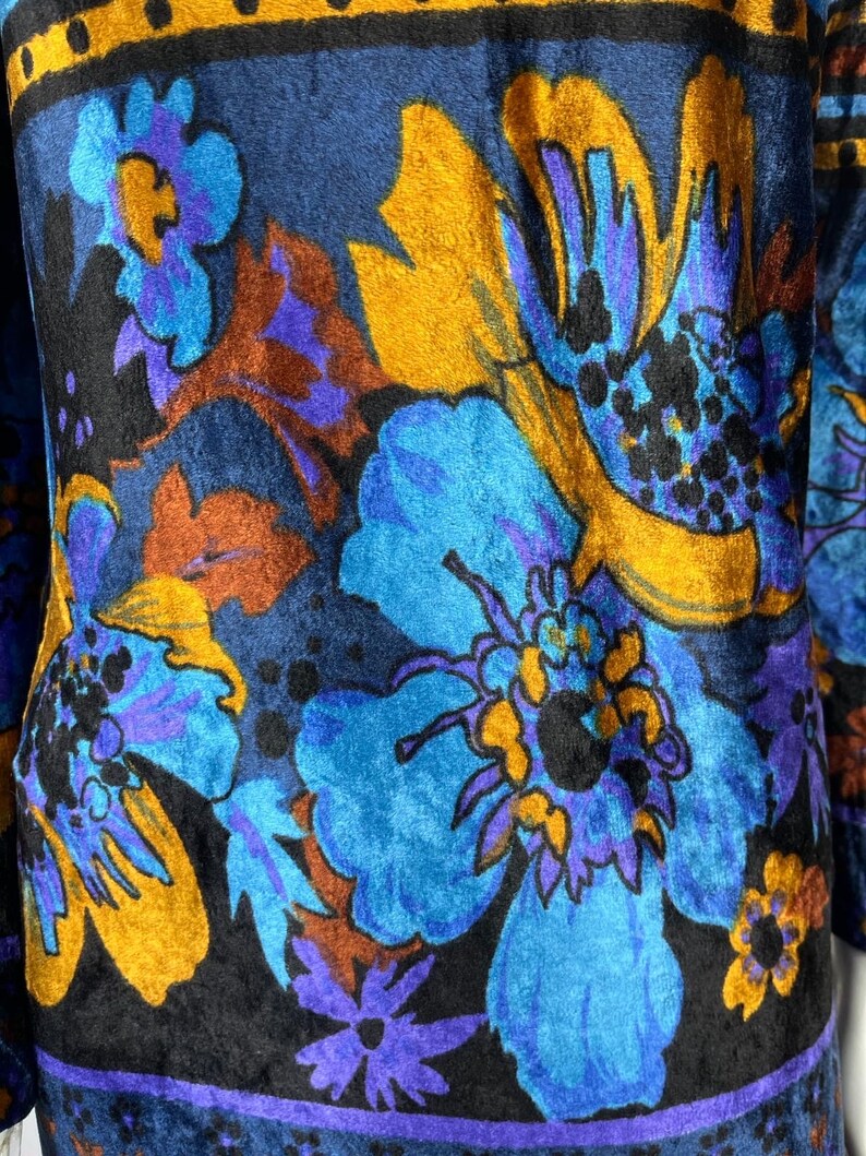 May include: A blue, black, and gold fabric with a floral pattern. The fabric has a velvety texture.