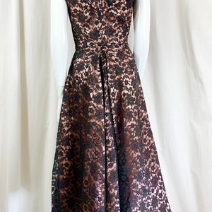 May include: A black lace dress with a brown lining. The dress has a V-neckline and short sleeves. The skirt is full and flowing.