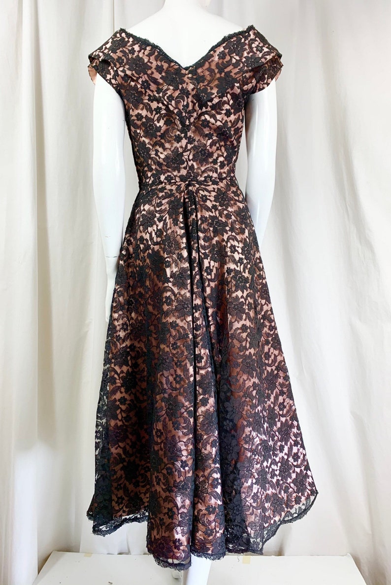 May include: A black lace dress with a brown lining. The dress has a V-neckline and short sleeves. The skirt is full and flowing.