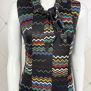 May include: A sleeveless dress with a black background and a colorful wavy pattern. The dress has a tie at the neck.