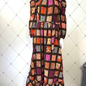 K&ouml;nnte beinhalten: Ein langes, schulterfreies Kleid mit Patchwork-Muster in Braun-, Orange-, Rosa- und Wei&szlig;t&ouml;nen. Das Kleid hat einen figurbetonten Oberteil und einen flie&szlig;enden Rock mit einem R&uuml;schen-Saum.