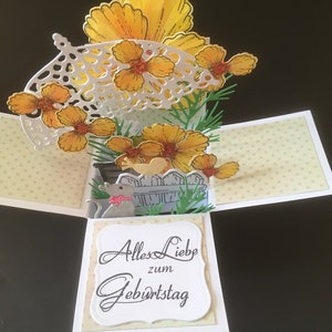 Puede incluir: Una tarjeta emergente con un diseño de flores amarillas y el texto "Alles Liebe zum Geburtstag".